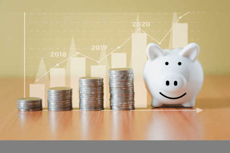 Stacking coins pile and white piggy bank for savings with money and planning step up to growing, Saving money for retirement fund and the future plan concept.の写真素材