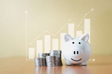 Stacking coins pile and white piggy bank for savings with money and planning step up to growing, Saving money for retirement fund and the future plan concept.の写真素材