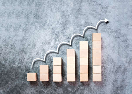 Wooden block stacking as ladder, step stairs with white arrow up on gray background, Concept of success in business growth, copy spaceの写真素材