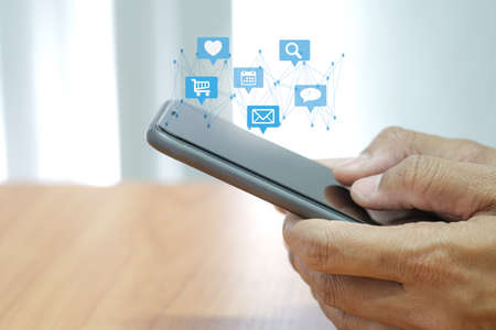 Social media interactions on smart mobile phone. Concept of notification icons of like, message, email and comment. Hands holding the device.の写真素材