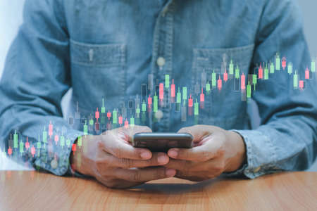 Concept digital money and stock business, Business men use smartphone with bar graph of stock and stock tableの写真素材