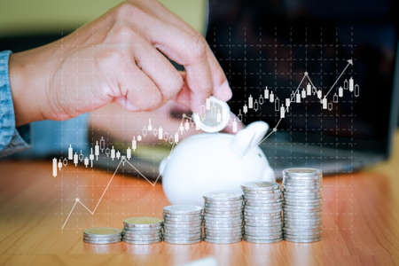 A businessman holding a blank note with coins stack placed on the front. Saving and investment concept for the future. copy space for text.の写真素材