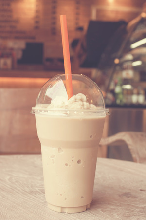 take-home cup of ice coffee on wooden table in coffee shop - vintage effect style picturesの写真素材