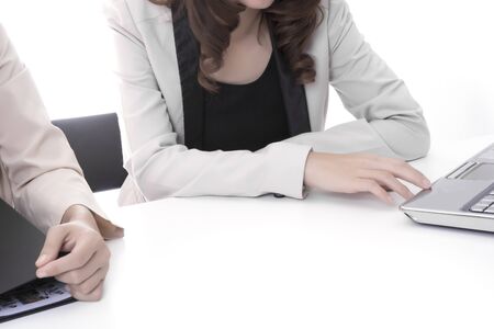 Two asian business woman in office, discussing profile with notebookの写真素材