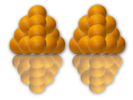 Two pyramids made of several oranges reflected on a surfaceの写真素材