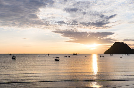 Beautiful sunrise over the sea with orange sky, clouds and fishing boatsの写真素材