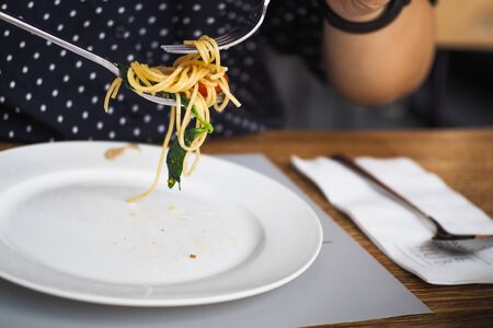 A girl eating pasta in the restaurantの写真素材