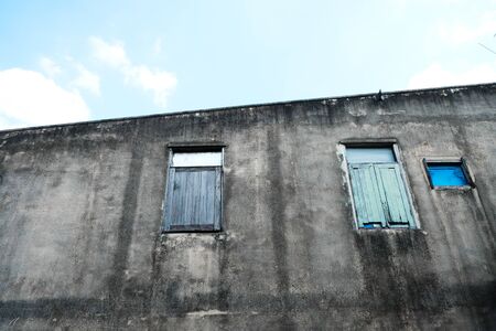 Old concrete wall and three windows with blue skyの写真素材