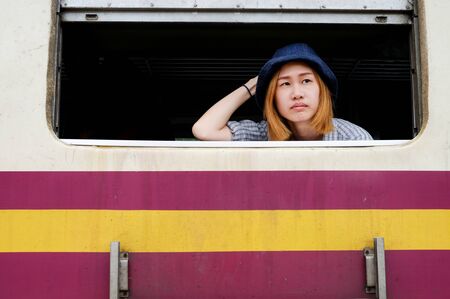Young asian blond hair woman looking out of the window on the trainの写真素材