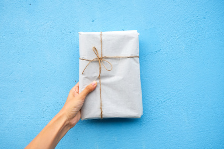Female hand holding gift box with blue backgroundの写真素材