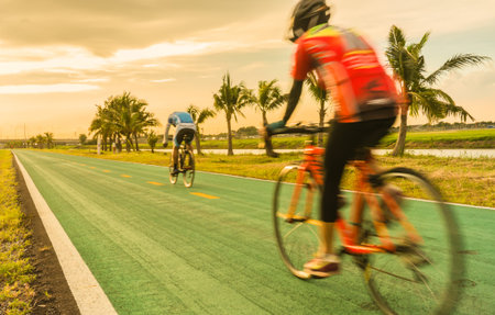 Two men spin bicycle moving in the sunsetの写真素材