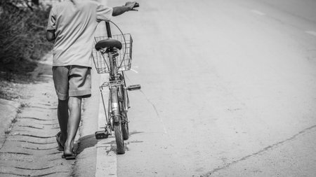 One boy tow old flat Tire bicycle back home. Black and White mood.の写真素材