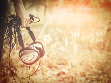 Girl hand Holding  long line Earphone in Meadow. vitage tone.の写真素材