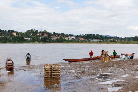 CHIANG RAI, THAILAND - JUNE 22, 2015: worker loading product to small boat  pass  Mekong River from thailand to border laos Country.のeditorial素材