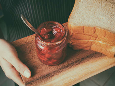 Red strawberry and peach yellow jam on plank wood and slice bread.の写真素材