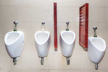 Line of white porcelain urinals in public toiletsの写真素材