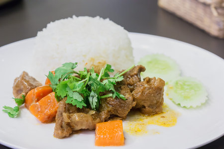 A meal of white rice and stew on a white plateの写真素材