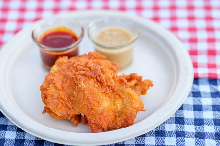 A plate of fresh, hot, crispy fried chicken on blue and red plaid towelの写真素材