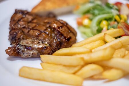 Black pepper pork steak served with bread and potato chipsの写真素材
