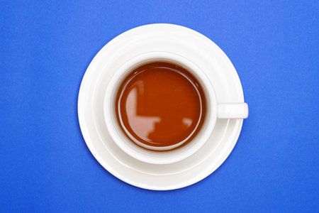 Coffee in a coffee cup top view on blue background