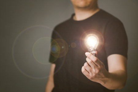 Man holds a light bulb in his hand with tech circles inside. The light emitted by the bulb, Idea inspired by online technology, Innovative concept.の写真素材
