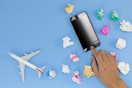 hand use smartphone with airplane model on blue backgroundの写真素材