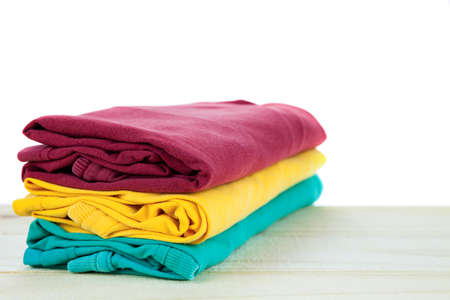 Pile of clothes t-shirt colorful clothing on wood,white backgroundの写真素材