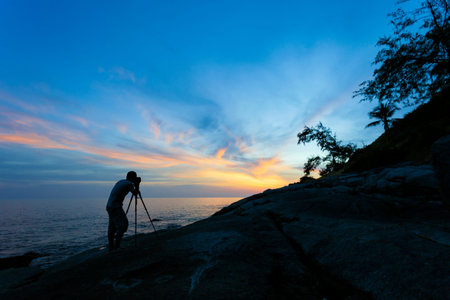 Silhouette of a photographer or traveler using a professional DSLR camera,photographer take sunset...