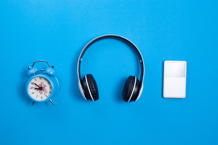wireless headphone and media player,blue alarm clock on blue paper background,image for media design and music website backgroundの写真素材