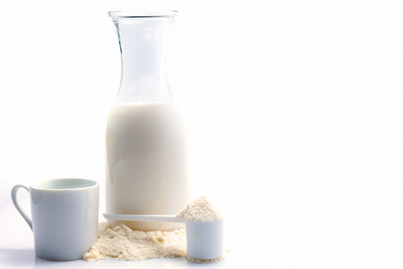 Bottle of fresh milk with powdered milk and spoon for baby on white backgroundの写真素材