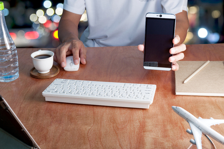 Businessman hold blank screen smartphone and use computer laptop in office,image for your ad text on smartphone,business sme banking background conceptの写真素材