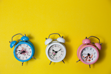 Flat lay retro beautiful new alarm clock on yellow paper pastel color background.の写真素材