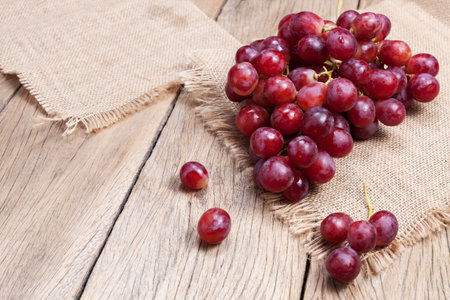Red grapes on old wooden table background