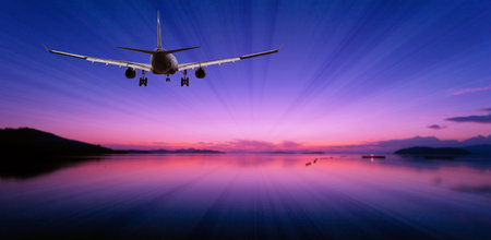 Airplane flying over tropical sea at beautiful light sunset or dramatic sky sunrise scenery background.の写真素材