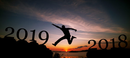 New year 2019 concept of Silhouette travel man jumping on the cliff in sunrise or sunset time to...