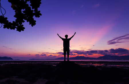 Alone man standing holding his hand up and see landscape scenery view in sunset time.の写真素材