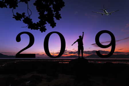 Silhouette freedom young man on the stone in sunrise or sunset over sea and 2019 years text,Happy new year 2019 concept background.の写真素材