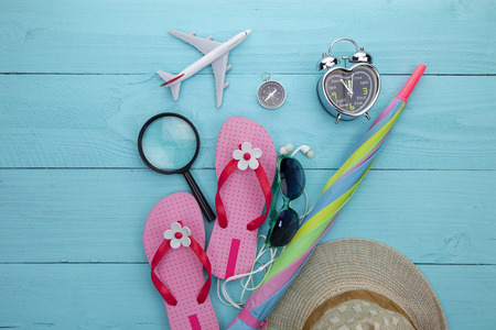 Beach accessory,hat,sunglasses,shoes,umbrella,airplane model,earphone,compass on blue wooden background, concept summer holiday travel background and summer sale.の写真素材