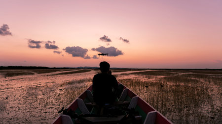 Silhouette Professional man controls drone in the boat Beautiful sky sunset or sunrise time.