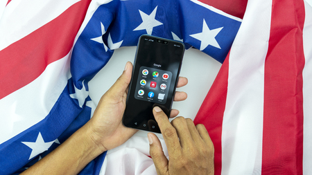 Phuket Thailand May-24-2019 Hand business asian man touch mobile smartphone Huawei Y9 2019 with american flag, Concept The conflict between China and the United States.のeditorial素材