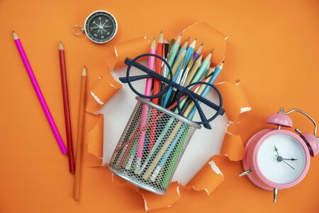 Education objects on orange ripped open paper background.の写真素材