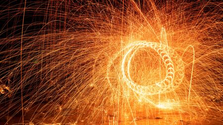Swing fire Swirl steel wool light photography over the stone with reflex in the water long exposure speed motion style.の写真素材