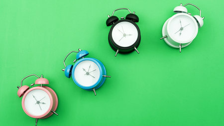 Flat lay retro beautiful new alarm clock on green background