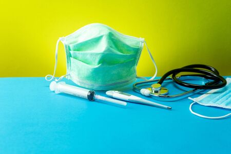 Coronavirus or Covid-19 Medical mask with Stethoscope,Electronic thermometer and syringe on blue tableの写真素材