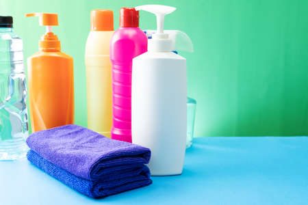 Plastic bottles of cleaning products set with pile clothes on tableの写真素材