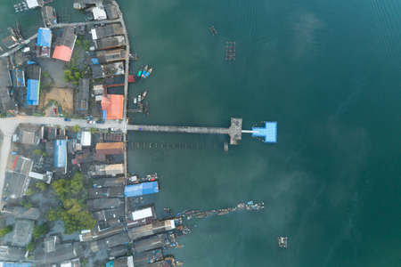 Aerial High angle view drone shot of long bridge in to the tropical sea with fisherman village.の写真素材