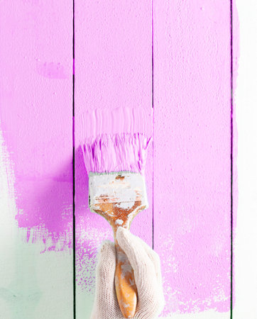 Close Up painter man Hand painting pink color on wooden plank table with copy space,bright creative design interior and How to Paint Wooden Surface.の写真素材