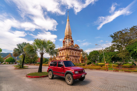 Red car Suzuki Vitara 1993 with pagoda in Phuket, Thailand - 9 December 2020 , The Phra Mahathat Chedi (Great Relic Stupa) Wat Chalong or Wat Chaithararam is famous tourist destination in Phuket.のeditorial素材