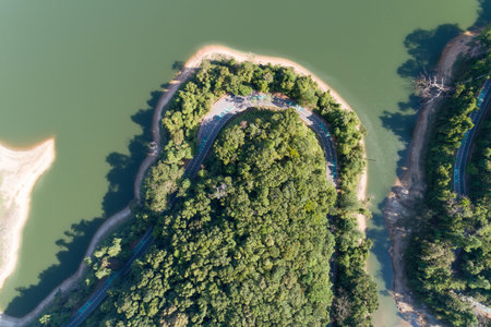 Top down from Drone aerial view of rainforest with asphalt road around the dam and shared land...