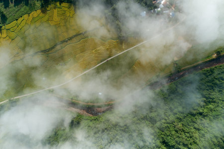 Aerial view drone shot of flowing fog waves on mountain tropical rainforest,Bird eye view image over the clouds Amazing nature background with clouds and mountain peaks in Nan Thailand.の写真素材